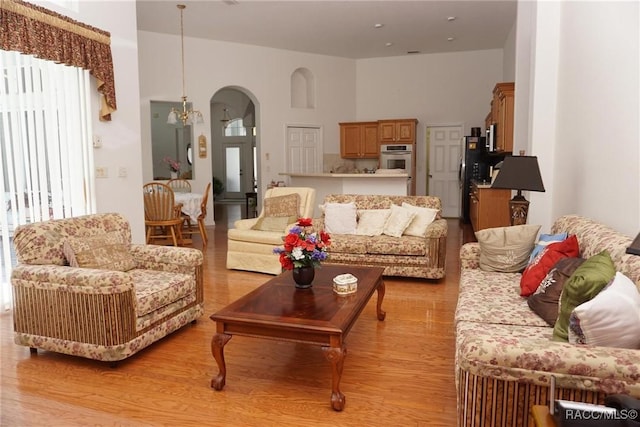 living area with light wood finished floors and arched walkways