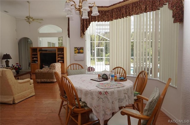 dining room with arched walkways, visible vents, ceiling fan with notable chandelier, and wood finished floors