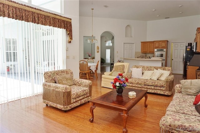 living area with light wood finished floors, arched walkways, and a notable chandelier