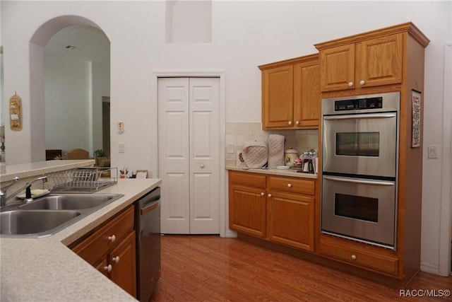 kitchen with light countertops, stainless steel appliances, wood finished floors, and a sink