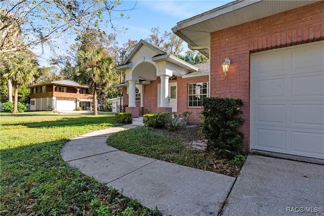 entrance to property featuring brick siding, a yard, and an attached garage