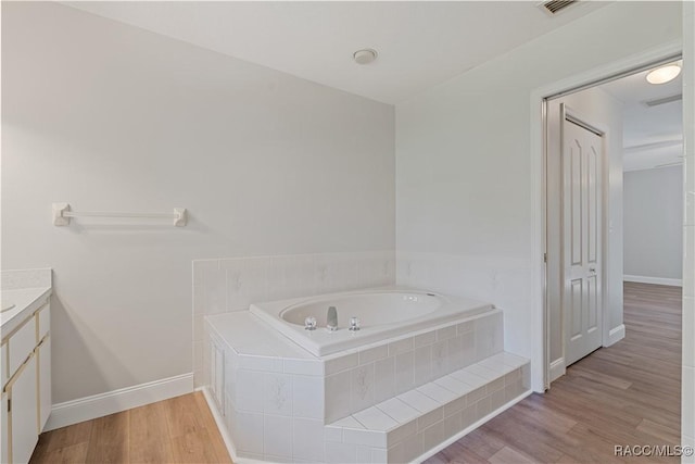 bathroom with vanity, a bath, baseboards, and wood finished floors
