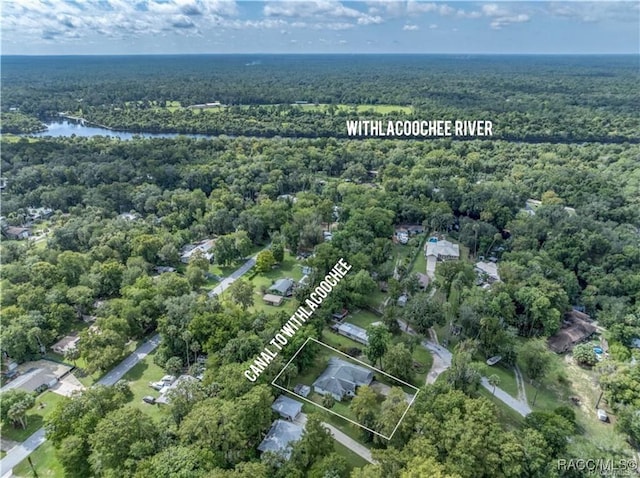 aerial view of property's location featuring a heavily wooded area and a nearby body of water