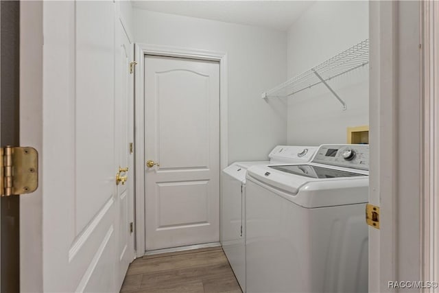laundry room with washer and clothes dryer and light wood finished floors