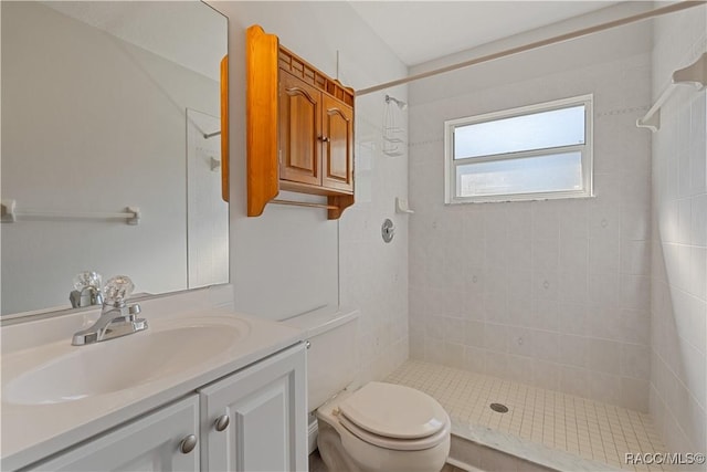 bathroom with a tile shower, vanity, and toilet