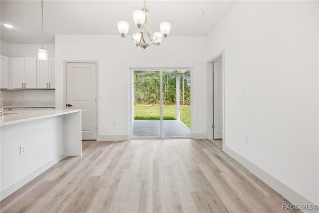 7820 N Sarazen Dr, Citrus Springs, FL 34434 - unfurnished dining area with a chandelier, light wood-style floors, a sink, and baseboards