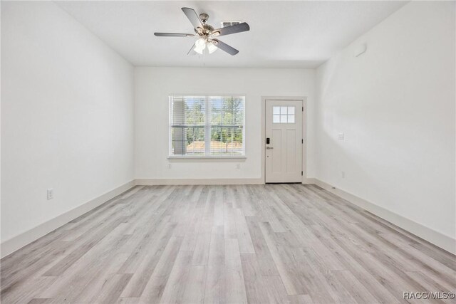 7820 N Sarazen Dr, Citrus Springs, FL 34434 - unfurnished living room featuring light wood-type flooring, a ceiling fan, and baseboards