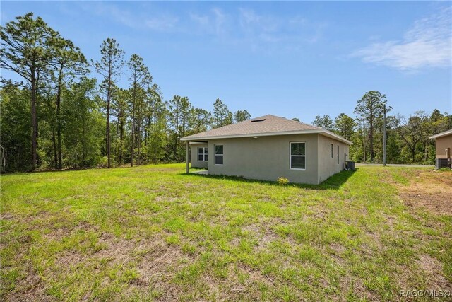 7820 N Sarazen Dr, Citrus Springs, FL 34434 - rear view of house featuring stucco siding and a yard