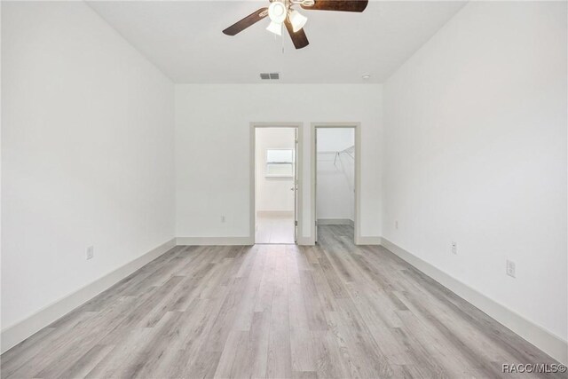 7820 N Sarazen Dr, Citrus Springs, FL 34434 - unfurnished bedroom featuring light wood-type flooring, a spacious closet, a closet, a ceiling fan, and baseboards
