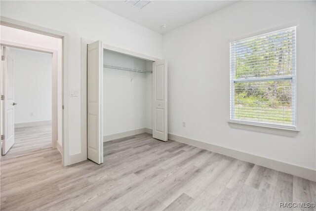 7820 N Sarazen Dr, Citrus Springs, FL 34434 - unfurnished bedroom featuring light wood finished floors, a closet, and baseboards