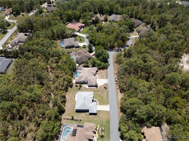 drone / aerial view with a wooded view and a residential view