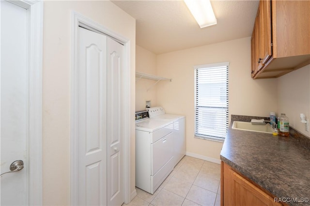 clothes washing area featuring washer and dryer, light tile patterned flooring, a sink, and cabinet space
