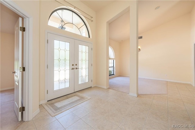 foyer entrance with light tile patterned floors, baseboards, visible vents, french doors, and lofted ceiling