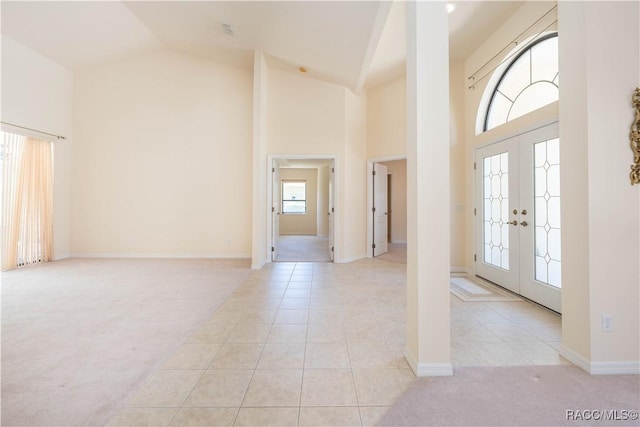 foyer with french doors, light tile patterned floors, high vaulted ceiling, and light colored carpet