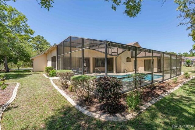 rear view of house featuring an outdoor pool, glass enclosure, a yard, stucco siding, and a patio