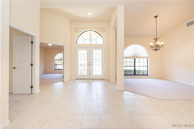 foyer entrance with an inviting chandelier, light colored carpet, a towering ceiling, and plenty of natural light