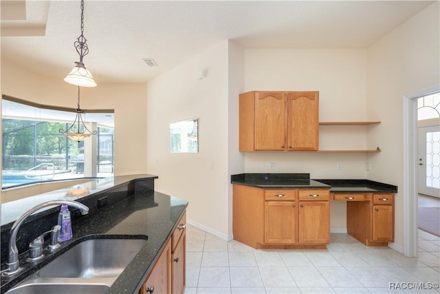 kitchen with light tile patterned floors, open shelves, decorative light fixtures, a sink, and dark stone counters