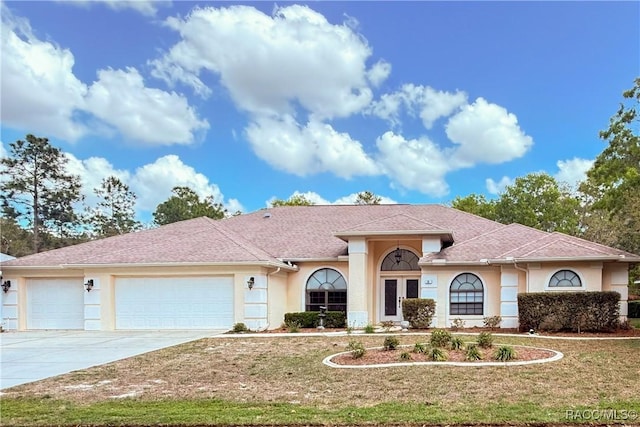 view of front of home featuring stucco siding, a front lawn, driveway, and a garage