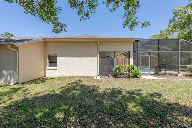 rear view of house with a yard, an outdoor pool, stucco siding, and glass enclosure
