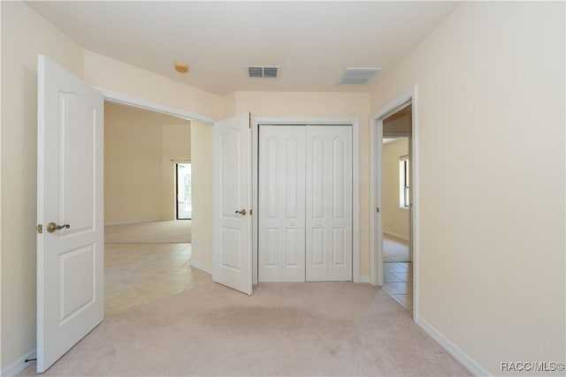 unfurnished bedroom with a closet, visible vents, and light colored carpet