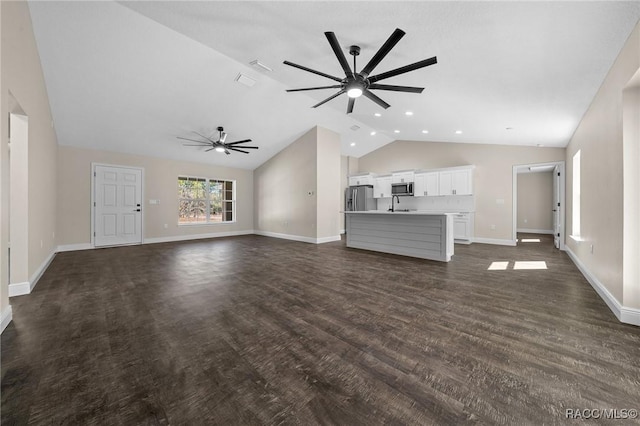 unfurnished living room with ceiling fan, sink, dark hardwood / wood-style flooring, and vaulted ceiling