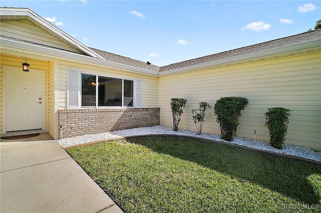 entrance to property with a lawn and brick siding