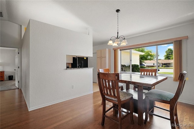 dining room featuring a chandelier, wood finished floors, and baseboards
