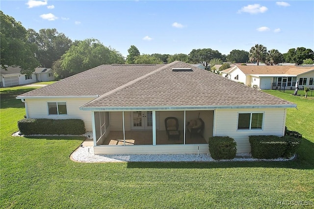 back of house featuring a yard, a sunroom, and a shingled roof
