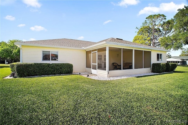 back of house featuring a sunroom, a lawn, and roof with shingles