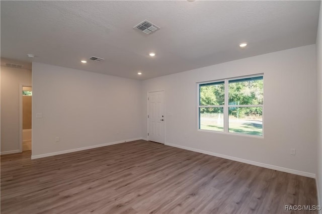 empty room with hardwood / wood-style floors and a textured ceiling