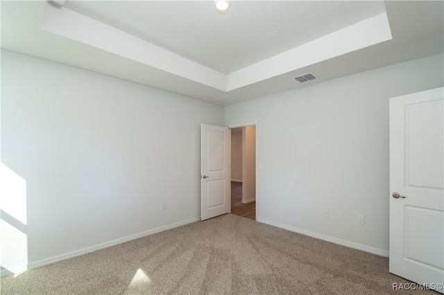 carpeted spare room featuring a raised ceiling