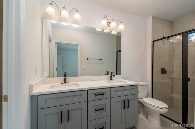 bathroom featuring a shower with door, vanity, and toilet