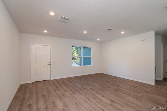 empty room with a textured ceiling and light wood-type flooring