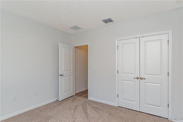 unfurnished bedroom with light carpet and a closet