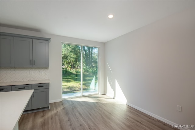 interior space with backsplash, gray cabinetry, and light wood-type flooring