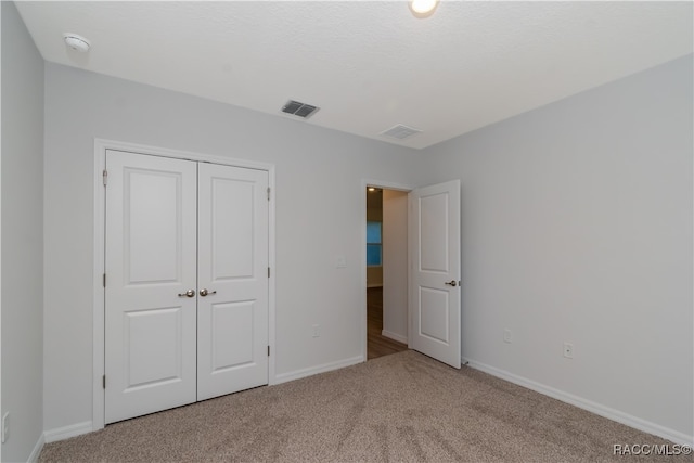 unfurnished bedroom featuring a closet and light colored carpet