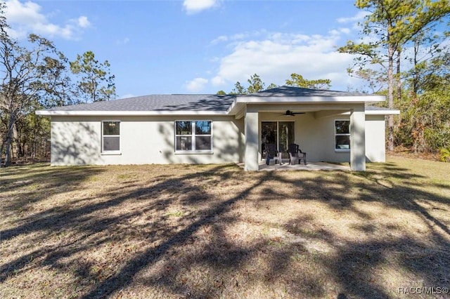 back of property featuring a ceiling fan, a patio area, a lawn, and stucco siding