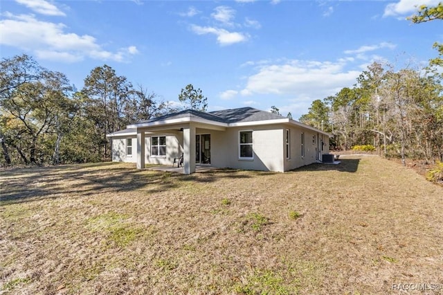 view of front of house featuring stucco siding, a patio, a front lawn, and central air condition unit