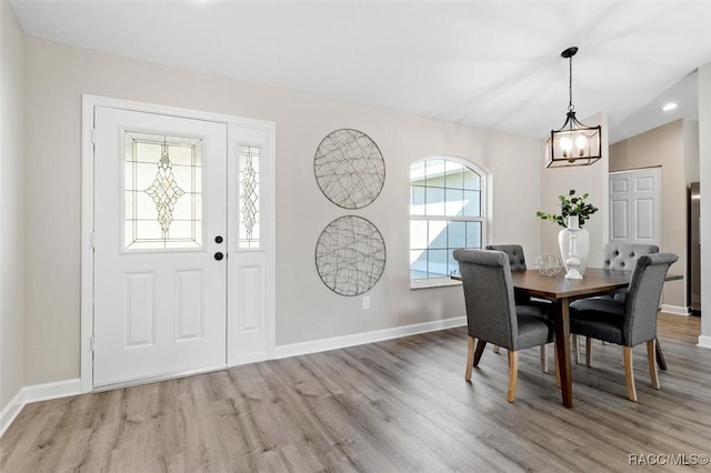 dining space featuring lofted ceiling, light wood-style flooring, and baseboards