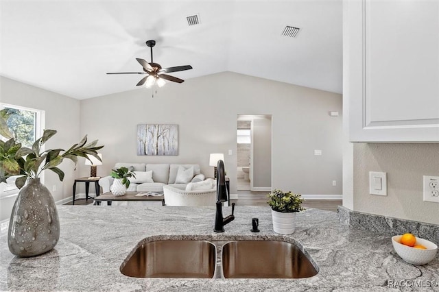 living area with vaulted ceiling, visible vents, and baseboards