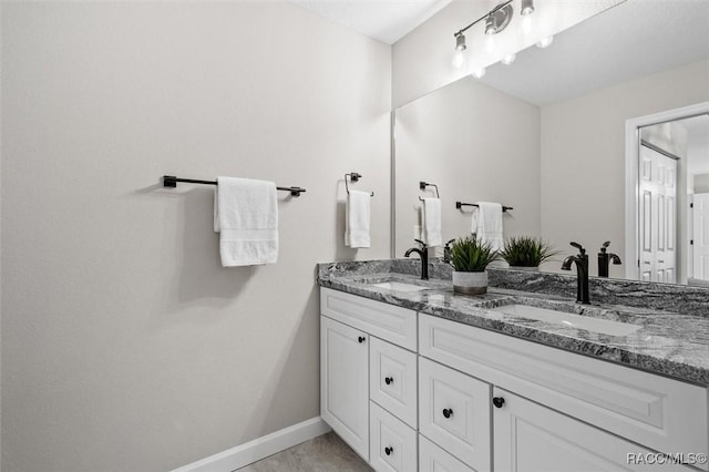 full bathroom featuring double vanity, baseboards, a sink, and tile patterned floors