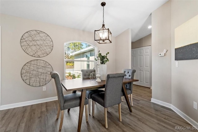 dining area featuring baseboards, vaulted ceiling, dark wood-type flooring, and a chandelier