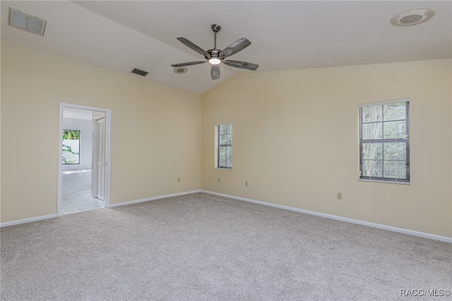 carpeted empty room featuring a textured ceiling, ceiling fan, plenty of natural light, and vaulted ceiling