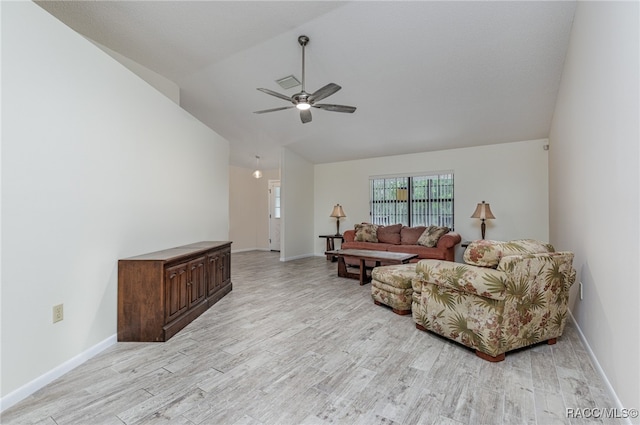 living room with ceiling fan, vaulted ceiling, and light wood-type flooring