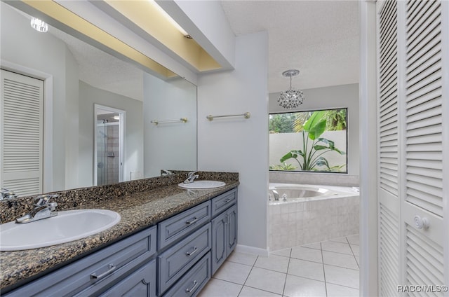 bathroom with tile patterned flooring, vanity, a textured ceiling, and tiled bath