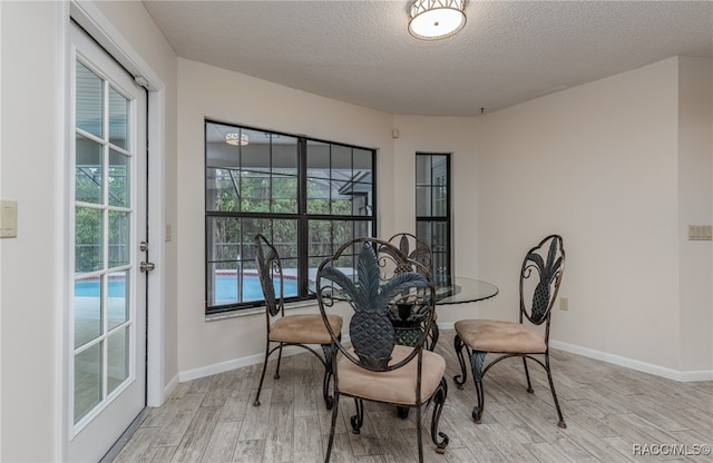 dining space with plenty of natural light, light hardwood / wood-style flooring, and a textured ceiling