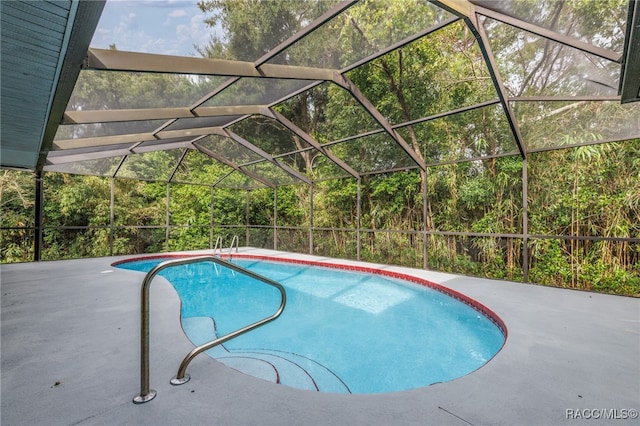 view of pool with glass enclosure and a patio