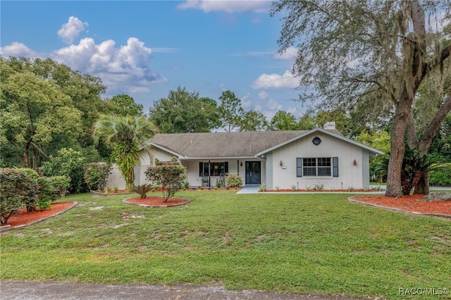 ranch-style home featuring covered porch and a front lawn