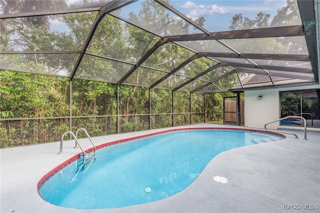 view of swimming pool featuring glass enclosure and a patio