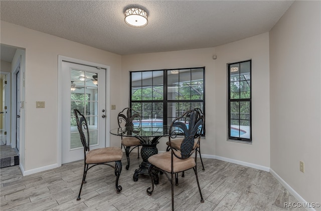 dining room featuring a textured ceiling, light hardwood / wood-style flooring, and ceiling fan